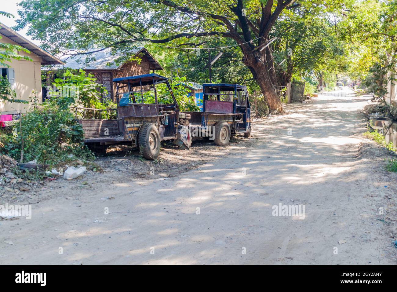 Rostige Fahrzeuge auf einer staubigen Straße in Mandalay, Myanmar Stockfoto