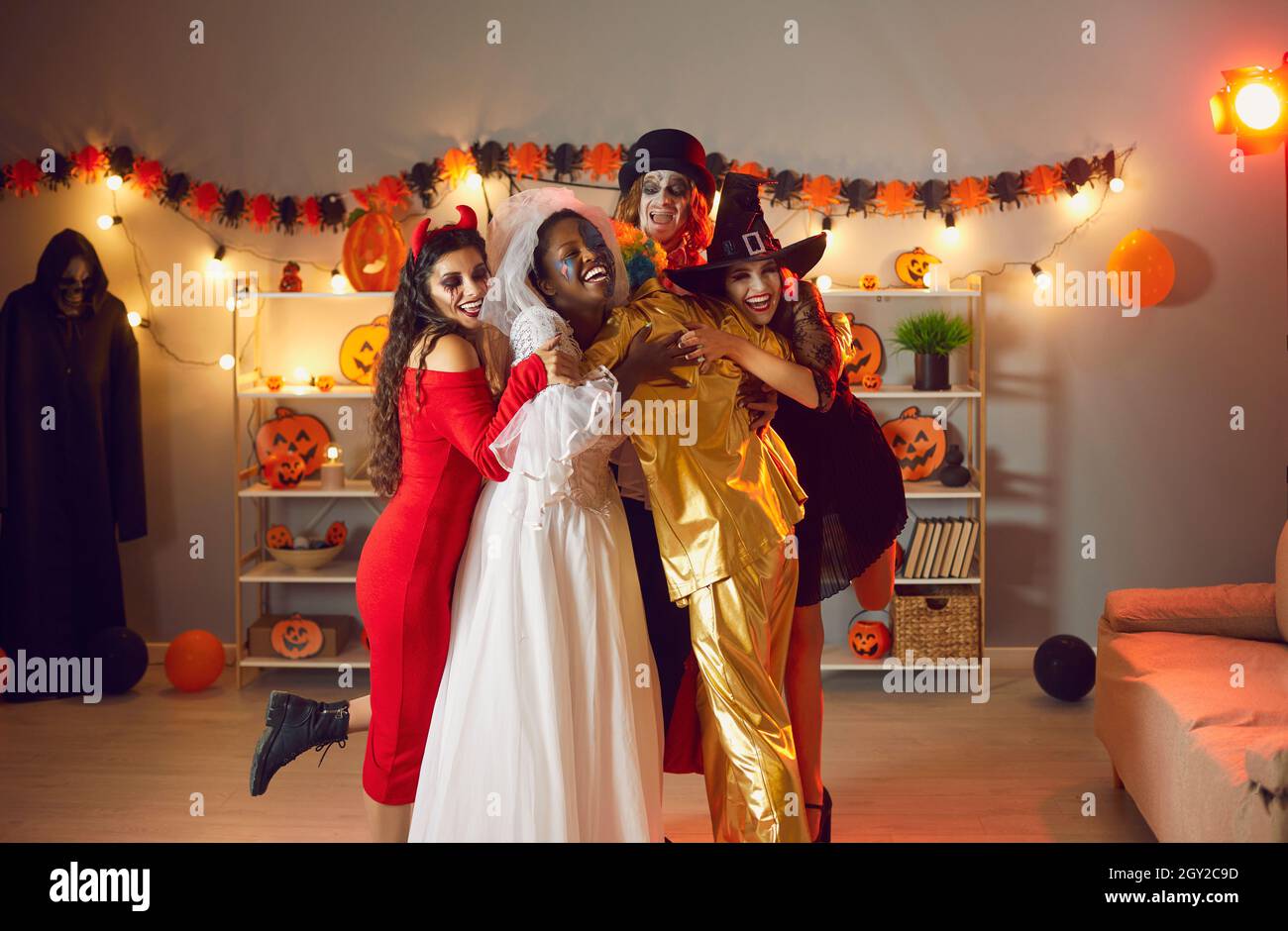 Eine Gruppe glücklicher junger Menschen in gruseligen Kostümen umarmte sich auf der Halloween-Party Stockfoto