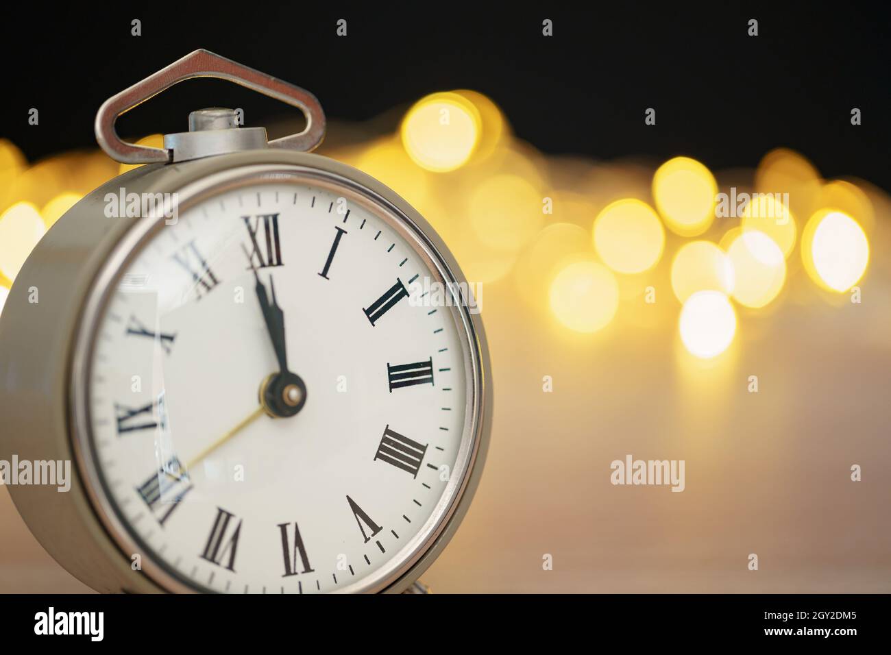 Nahaufnahme des Retro-Weckers auf verschwommenem Weihnachtshintergrund mit Bokeh Stockfoto