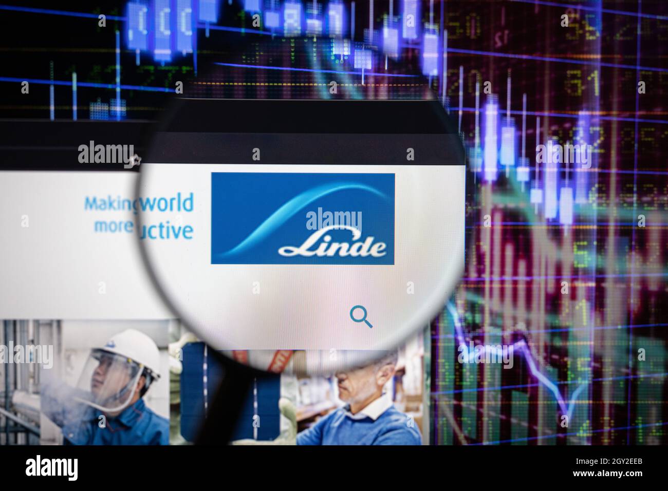 Linde-Firmenlogo auf einer Website mit verschwommenen Börsenentwicklungen im Hintergrund, die auf einem Computerbildschirm durch eine Lupe gesehen werden Stockfoto