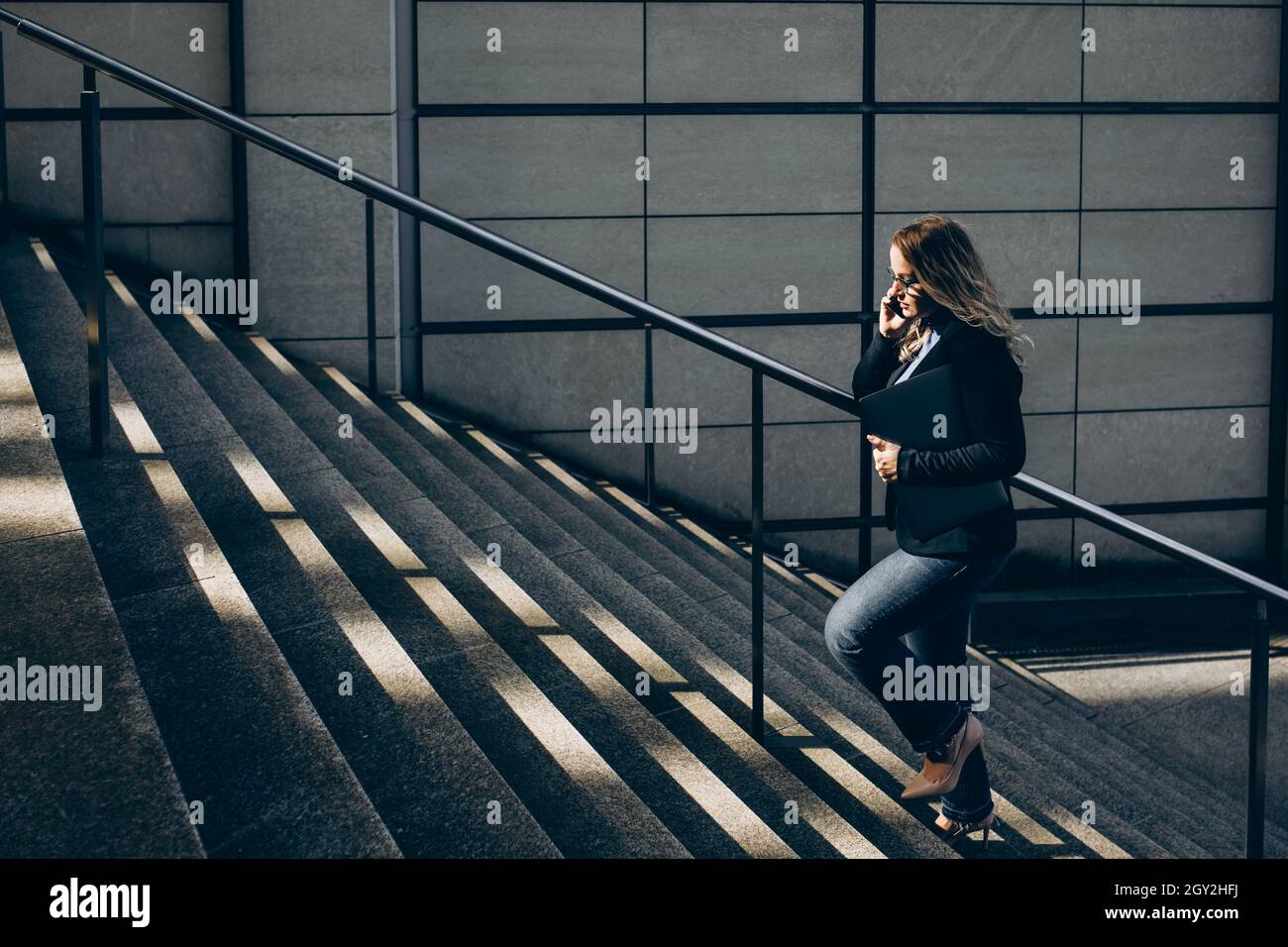 Geschäftsfrau mit Laptop geht die Treppe hoch. Stockfoto