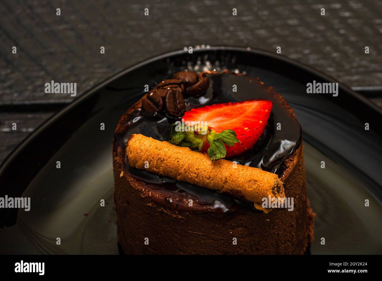 Nahaufnahme eines Schokoladenmousse-Dessert mit Zimt, einer geschnittenen Erdbeere auf einem Tablett Stockfoto