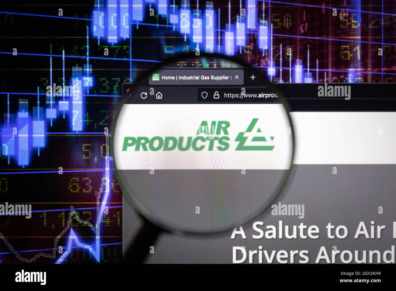 Logo des Unternehmens Air Products auf einer Website mit verschwommenen Börsenentwicklungen im Hintergrund, die auf einem Computerbildschirm durch eine Lupe gesehen werden Stockfoto