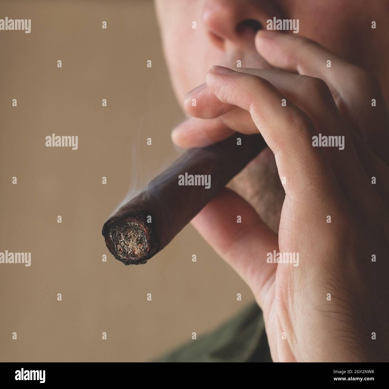 Ein Mann raucht eine kubanische Zigarre. Nahaufnahme einer rauchenden Zigarre. Stockfoto