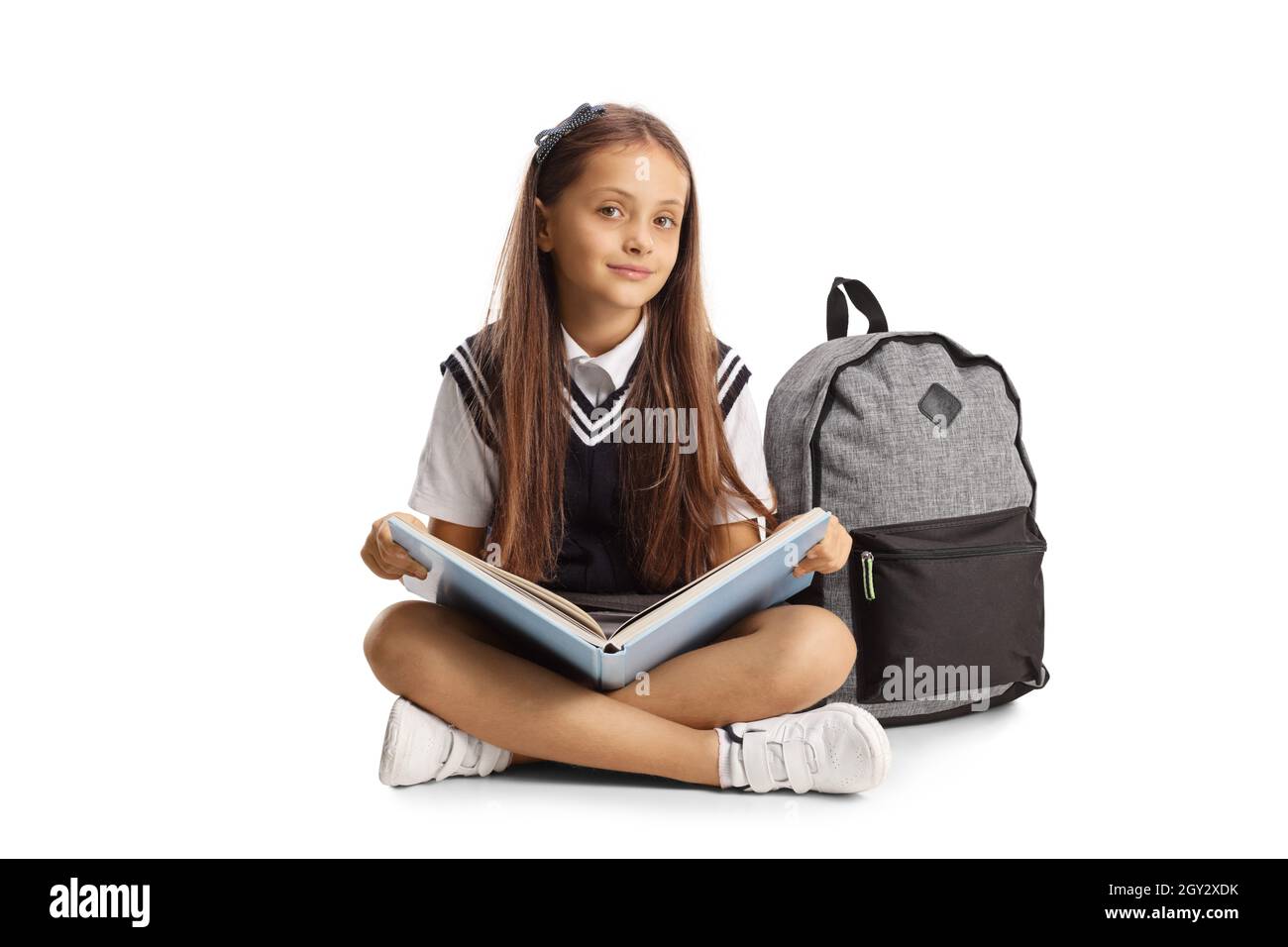 Schülerin sitzt auf dem Boden mit einem Buch auf ihrem Schoß isoliert auf weißem Hintergrund Stockfoto