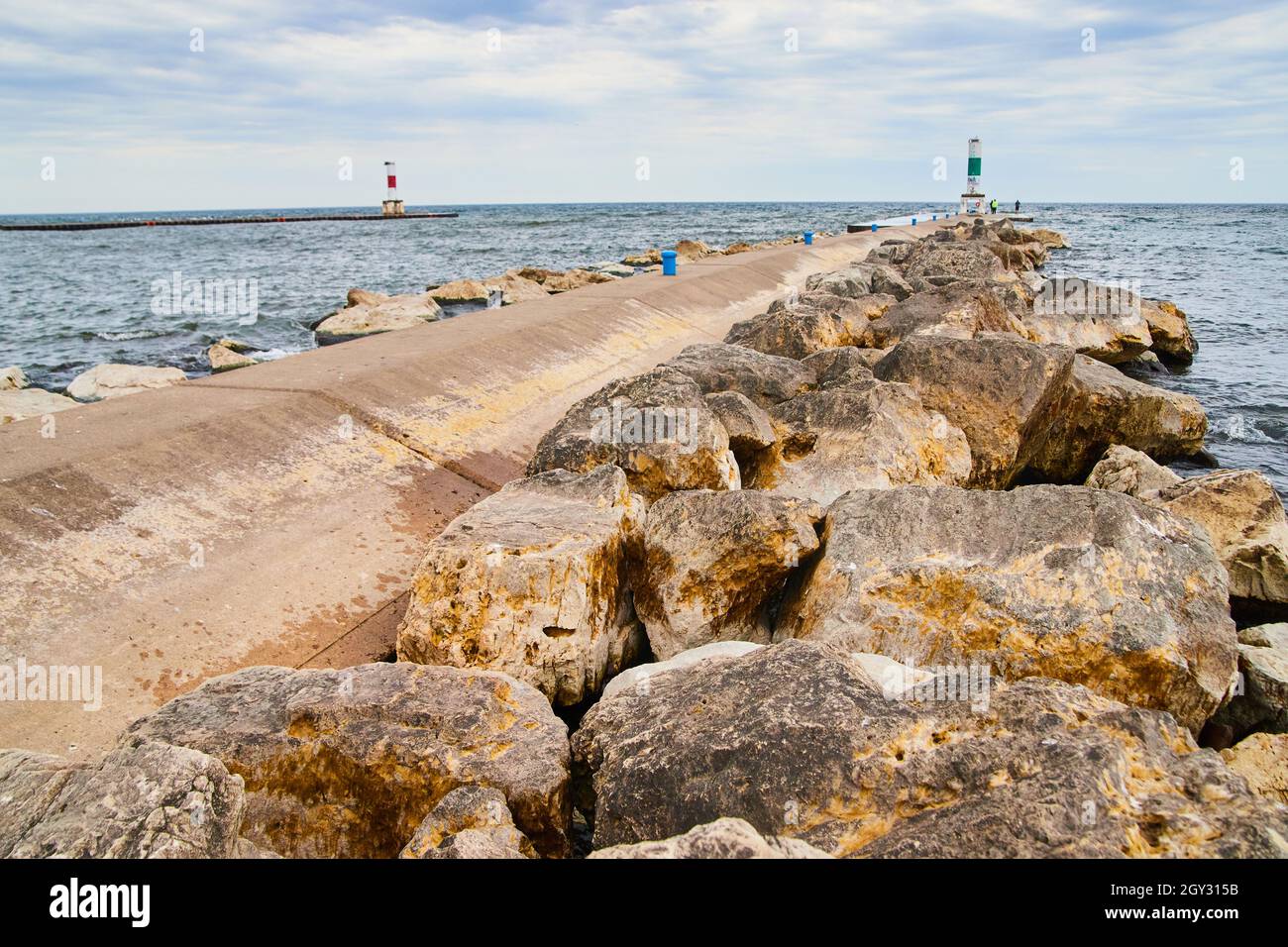 Großer Zementpier am See, gesäumt von Felsbrocken Stockfoto