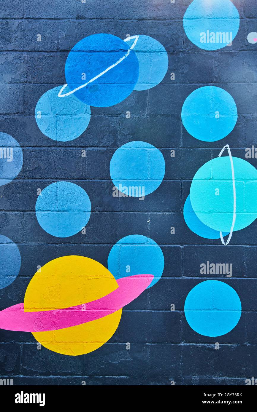 Zementwand mit schwarzen und blauen Flecken und Planeten bemalt Stockfoto