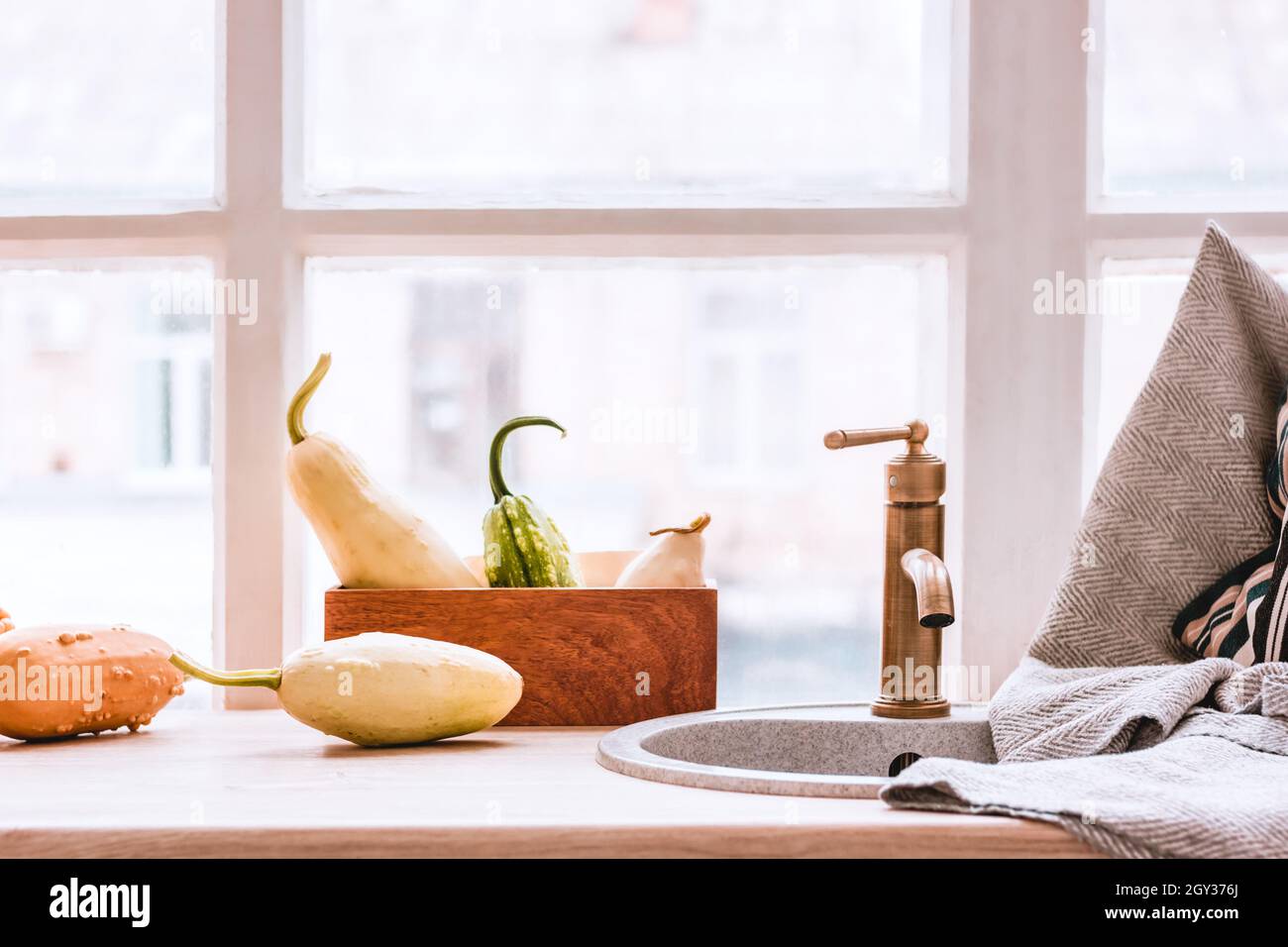 Hygge Vintage Kupfer Küchenarmatur und Handtuch auf einem Holztisch vor dem Fenster. Kürbissaison und herbstliche Innenarchitektur mit gemütlichen Dekorationselementen Stockfoto