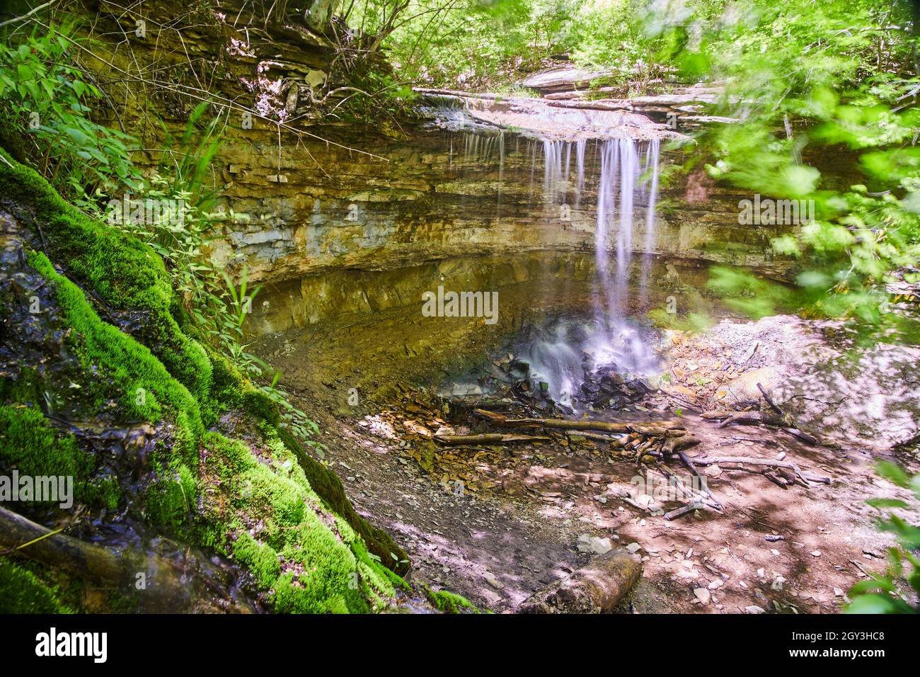 Wasserfall über einer kleinen Klippe neben einem moosigen Hügel Stockfoto