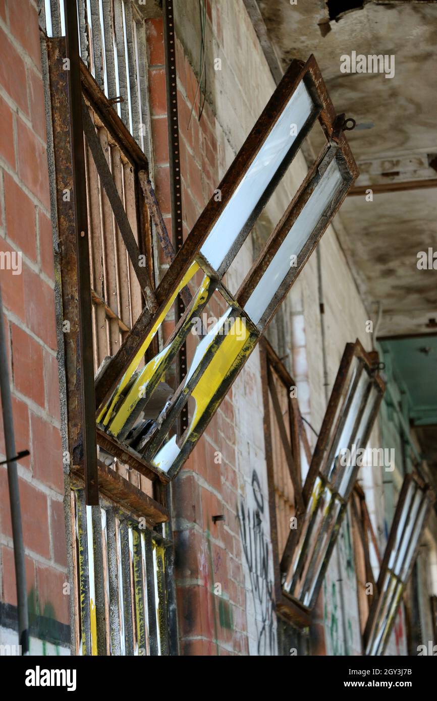 Verrostete Vintage-Trichterfenster kippen in einem alten, verlassenen Gebäude nach innen. Stockfoto