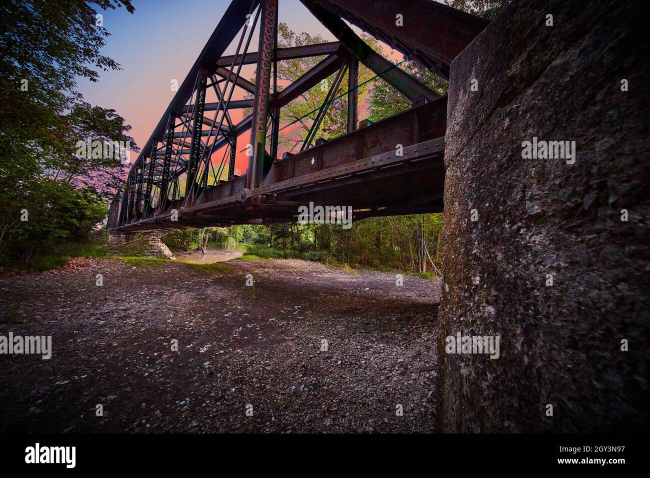Ansicht über die Brücke Unterstützung für Bahngleise mit intensiven Sonnenuntergang rosa Farbe Stockfoto