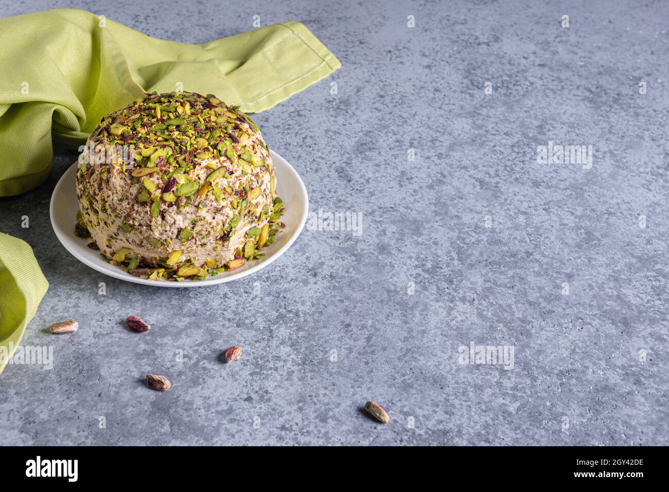 Halva mit Pistazien auf der Oberseite, wenigen verstreuten Nüssen, grüner Leinenserviette und großem Kopierraum. Traditionelle süsse aus dem Nahen Osten. Jüdisch, türkisch, arabisch Stockfoto