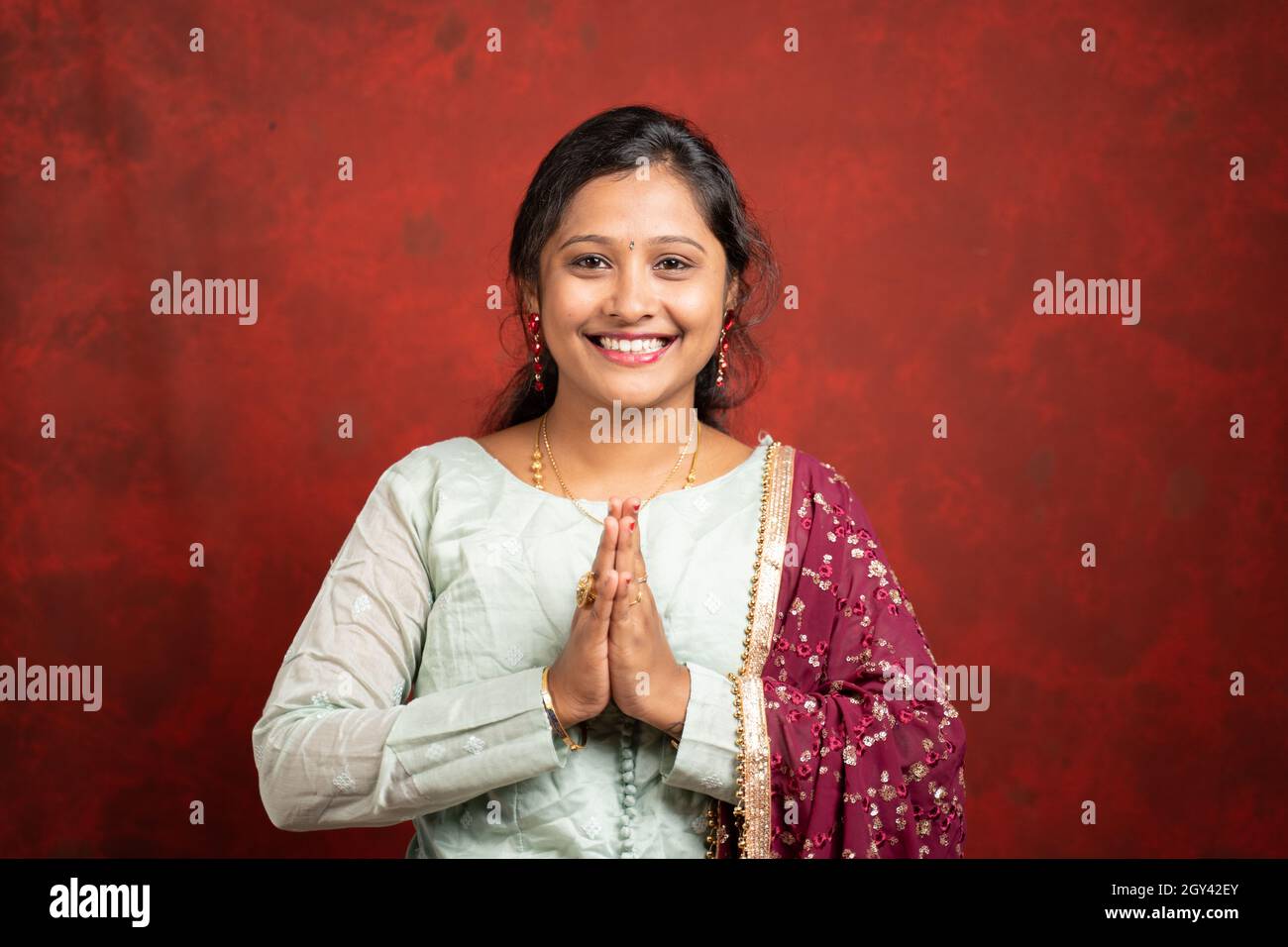 Glücklich lächelndes indisches Mädchen mit traditionellen ethnischen Kleid in namaste Geste Blick auf Kamera - Konzept der indischen Art der Begrüßung Stockfoto