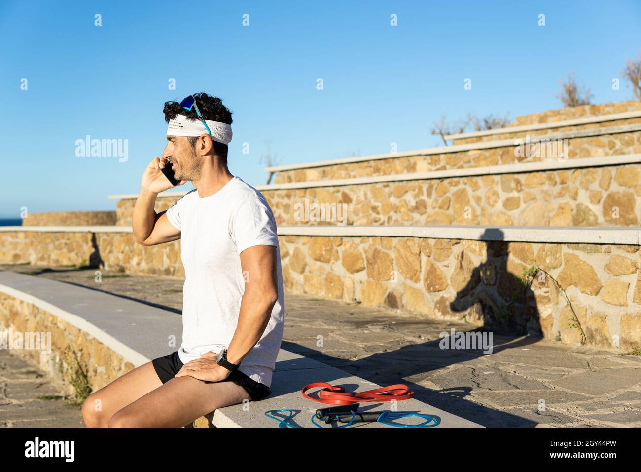 Junger kaukasischer Mann im Gespräch auf einem Smartphone in einem Outdoor-Park w Stockfoto