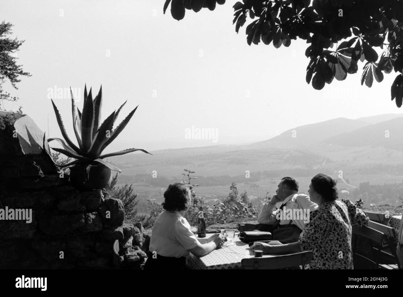 Zwei Damen und ein Herr genießen bei einem erfrischenden getränkt in der Sonne sterben Aussicht in das Schwarzatal, Deutschland 1930erJahre. Zwei Frauen und ein Mann sind, genießen Sie den Blick über die Schwarza Valley, während Sie einen erfrischenden Drink in der Sonne, Deutschland 1930. Stockfoto