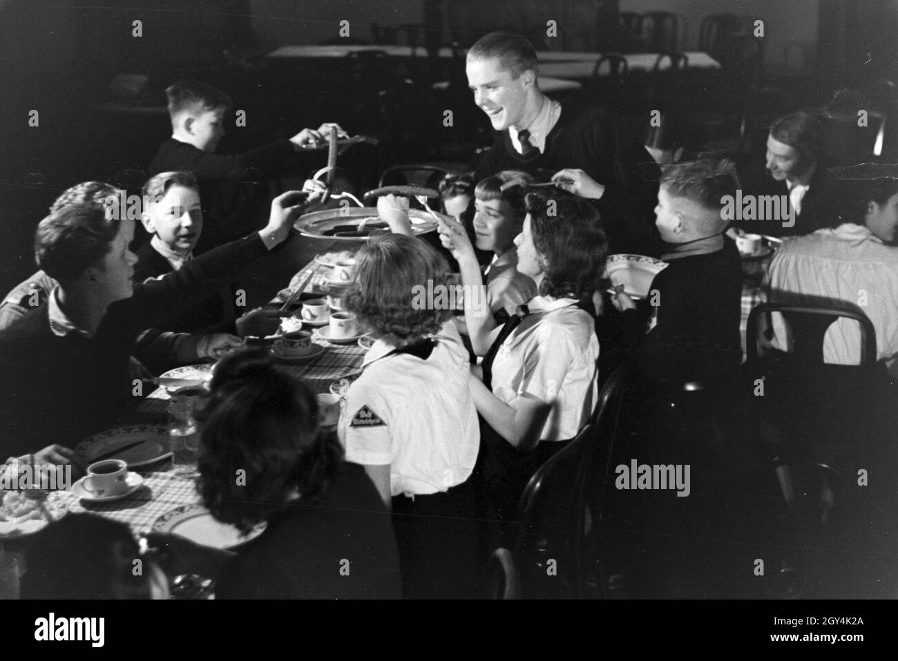 Eine Eiskunstlauf Gruppe der Hitlerjugend in den Uniformen der HJ und des BDM 5/6 des Essen nach dem Training, Deutschland 1930er Jahre. Eine figureskating Gruppe der Hitlerjugend das Tragen von Uniformen der HJ und BDM beim Abendessen nach einem Training, Deutschland 1930. Stockfoto