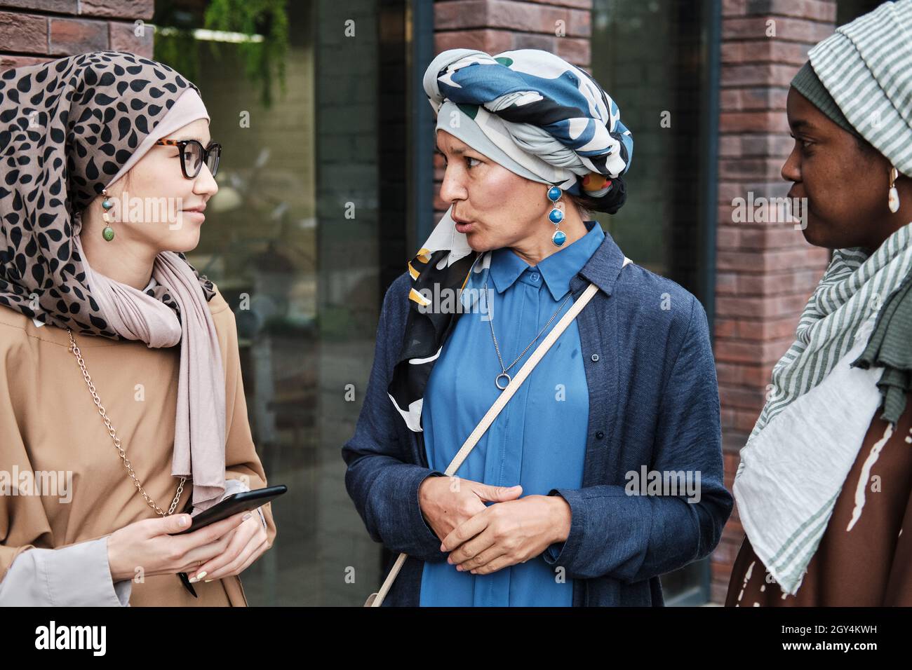 Elegante muslimische Frauen sprechen miteinander, während sie während ihres Treffens auf der Straße stehen Stockfoto