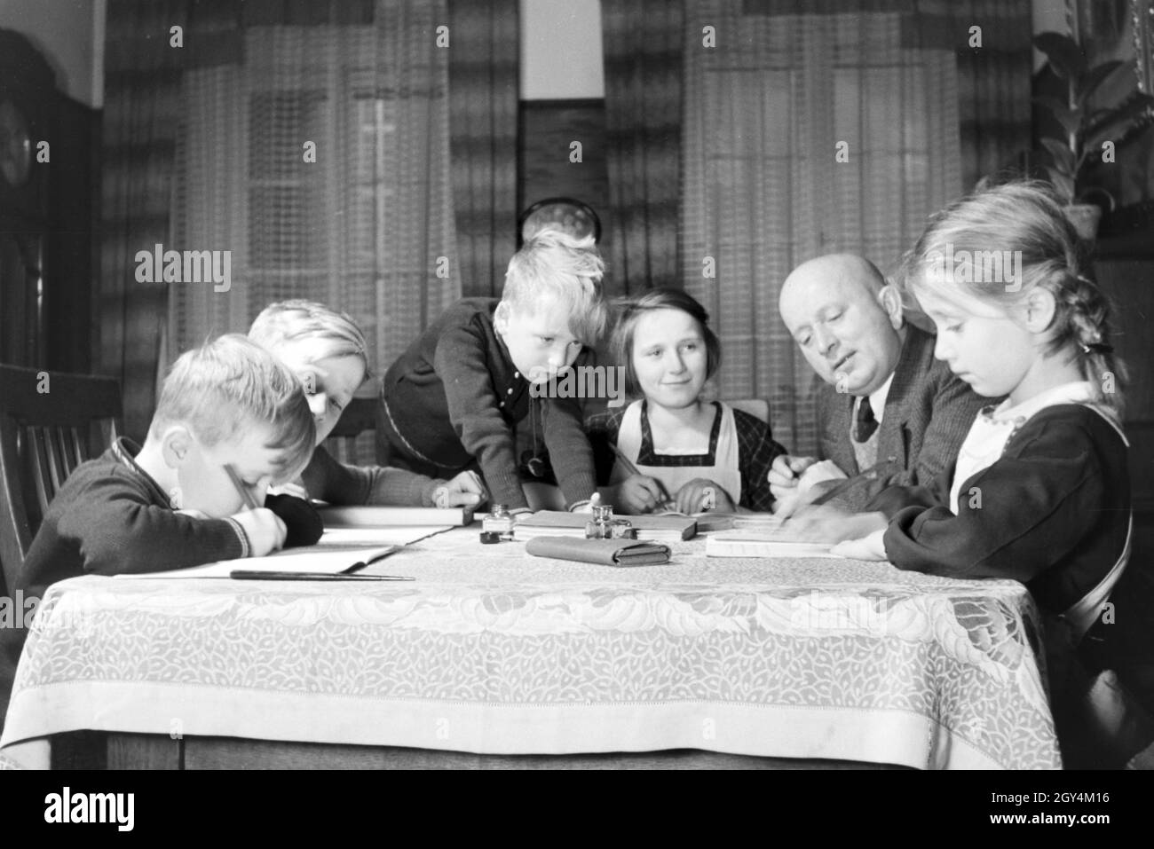 Mitglieder einer kinderreichen Familie bei den Hausaufgaben, Deutsches Reich 30er Jahre. Mitglieder einer Großfamilie, die Hausaufgaben, Deutschland 1930. Stockfoto
