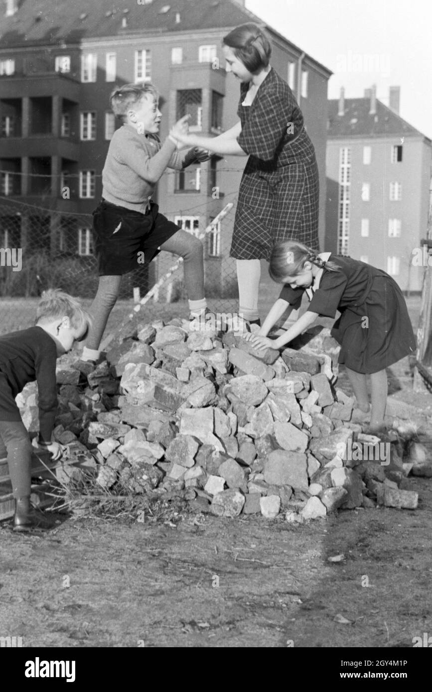 Mitglieder einer kinderreichen Familie spielen hinter dem Wohnhaus, Deutsches Reich 30er Jahre. Mitglieder einer Großfamilie spielen hinter dem Wohnblock, Deutschland 1930. Stockfoto