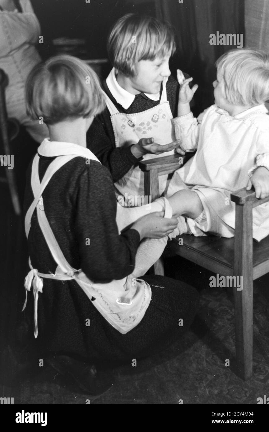 Zwei der Vierlinge von Brücken kümmern sich um Ihr jüngstes Geschwisterkind, Deutsches Reich 30er Jahre. Zwei der vierlinge von Brücken auf der Suche nach ihrer jüngsten Geschwister, Deutschland 1930. Stockfoto