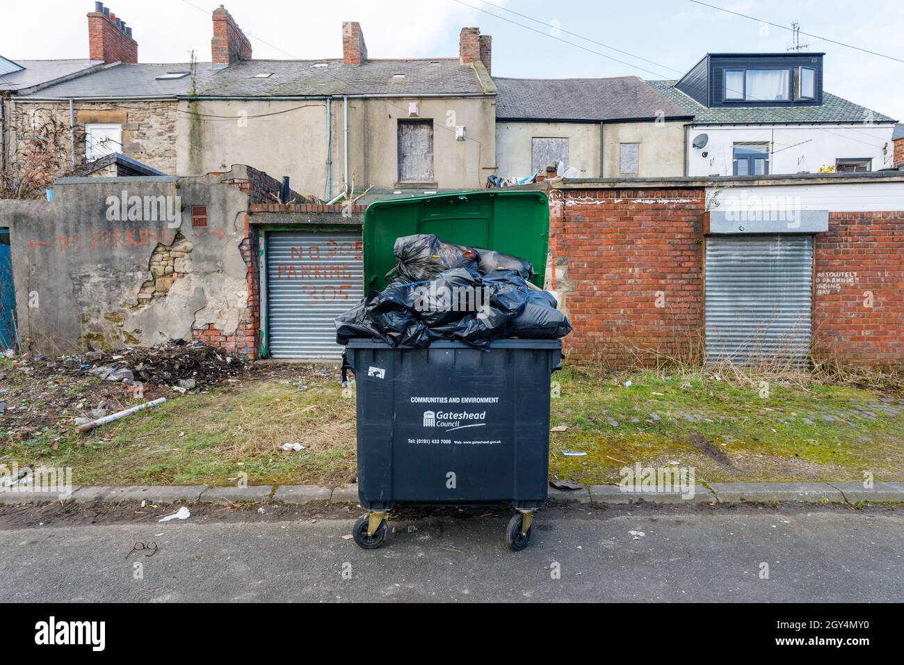 Gateshead UK: 6. März 2021: Ein übervoller Mülltonne in der schmutzige Hintergasse in Gateshead England Stockfoto