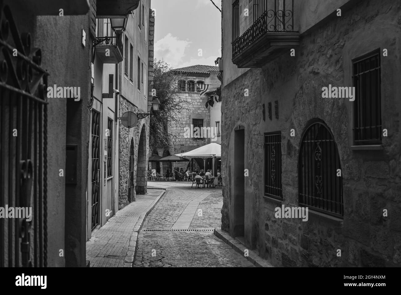 MONTBLANC, SPANIEN - 12. SEPTEMBER 2021: Schwarz-weiß Vintage Straßenbild von Menschen im Straßencafé Stockfoto
