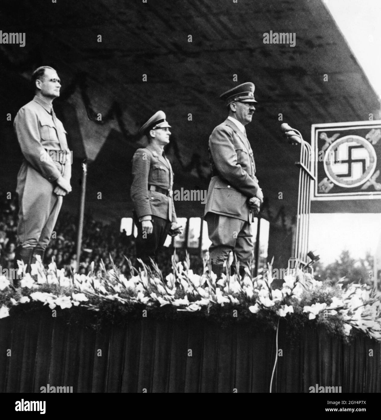 Hitler spricht auf der Parteikonferenz 'Großdeutschland' im Jahr 1938 an die Menge. Hinter ihm sein Stellvertreter Heß und der Reichsjugendführer Baldur von Schirach, der bei solchen Anlässen immer dabei war, als Gruppen der Hitlerjugend aufmarschierten. [Automatisierte Übersetzung]' Stockfoto
