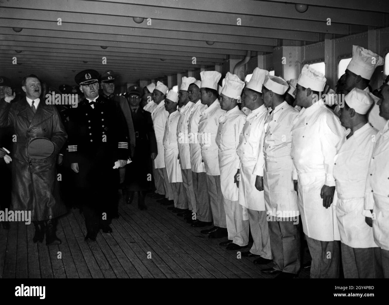 Adolf Hitler besucht zusammen mit Kapitän scharf das Passagierschiff Europa. Zusammen mit Admiral Raeder und General Werner von Blomberg laufen Sie auf dem Zwischendeck vor den Köchen des Schiffes. [Automatisierte Übersetzung] Stockfoto