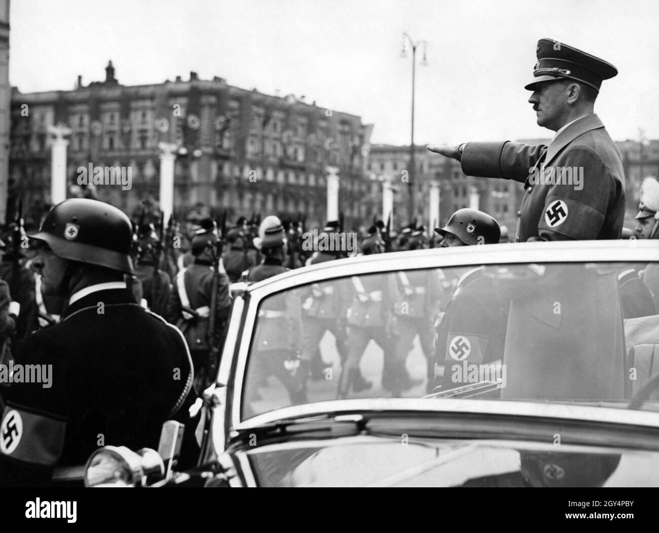 Adolf Hitler begrüßt Polizeieinheiten, die mit einem Mercedes W 150 Cabriolet am Wilhelmplatz vorbeimarschieren. Vor dem Auto stehen der Kommandant der Leibstandarte Adolf Hitler, Obergruppenführer Sepp Dietrich und Reichsleiter SS Heinrich Himmler. Dies war das erste Jahr, in dem SS-Angehörige diese herausragende Stellung innehaten, nachdem zuvor Angehörige der Wehrmacht mit Hitler in der ersten Reihe gestanden hatten. [Automatisierte Übersetzung] Stockfoto