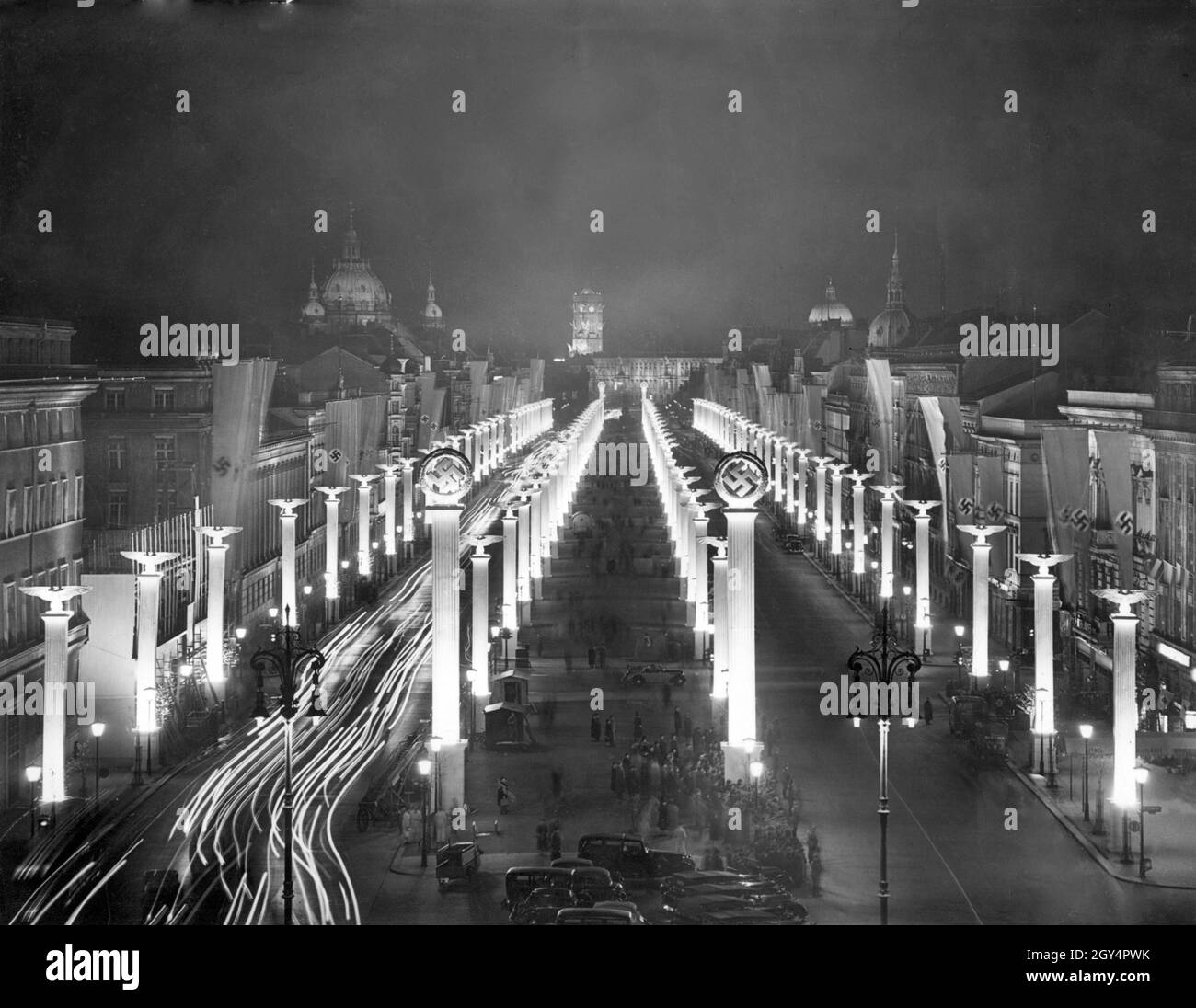 Blick vom Brandenburger Tor auf die mit Hakenkreuzen, Reichsadlern und Hakenkreuzfahnen geschmückte Straße unter den Linden am 19. April 1939, dem Abend vor Adolf Hitlers 50. Geburtstag. Im Hintergrund auf der linken Seite sehen Sie den Berliner Dom, auf der rechten Seite den. Turm des Roten Rathauses und daneben die Kuppel des Berliner Schlosses. [Automatisierte Übersetzung] Stockfoto