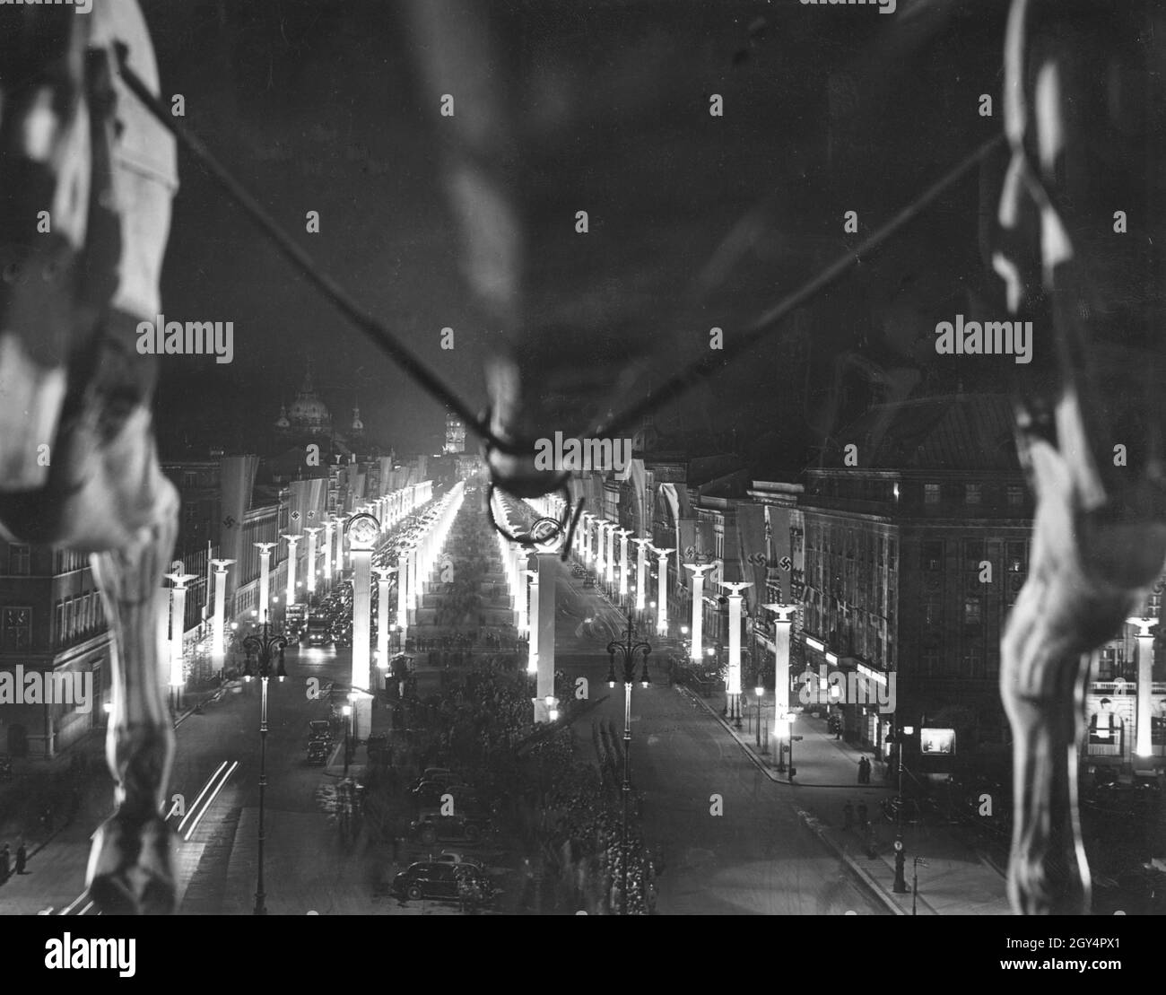 Blick von der Quadriga am Brandenburger Tor auf die mit Hakenkreuzen, Reichsadlern und Hakenkreuzfahnen geschmückte Straße unter den Linden am 19. April 1939, dem Abend vor Adolf Hitlers 50. Geburtstag. Im Hintergrund links sehen Sie den Berliner Dom. [Automatisierte Übersetzung] Stockfoto