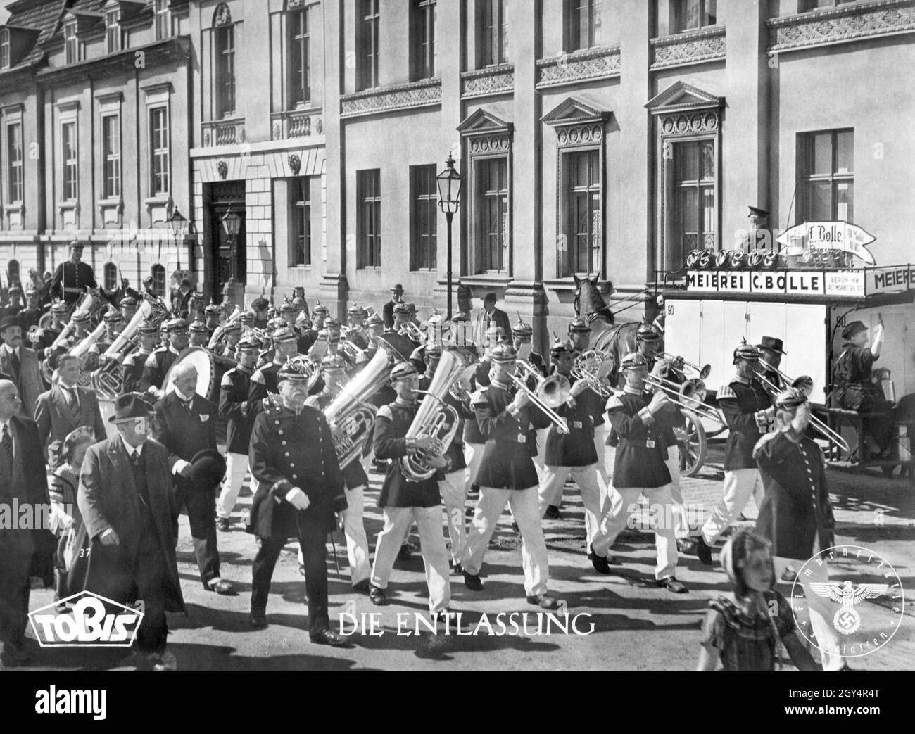 '1942 wurde die Wilhelmstraße in Berlin-Mitte in den UFA-Studios in Babelsberg (damals: Neubabelsberg) für die Dreharbeiten zum NS-Geschichtsfilm 'die Entlassung' rekonstruiert, da die echte Wilhelmstraße bereits von zahlreichen alliierten Luftangriffen auf Berlin gezeichnet war und nicht mehr für historische Außenaufnahmen genutzt werden konnte. Eine Militärkapelle marschiert durch die Straße, begleitet von Passanten. Das Siegel der Filmprüfstelle ist auf der Aufnahme zu sehen (rechts). [Automatisierte Übersetzung]' Stockfoto