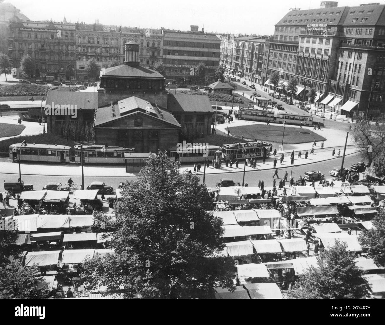 Der Wittenbergplatz in Berlin-Schöneberg ist am 13. Mai 1938 von den Ständen eines Wochenmarktes gesäumt. Hinter der U-Bahn-Station sind Häuser mit Geschäften und Pubs wie: ''H. Bergmann Färberei u. ehem. Waschanstalt'' und ''Münchener Löwenbräu''. Auf der rechten Seite wirbt das Kaufhaus des Westens mit ''alles für den Frühling aus dem KaDeWe''. [Automatisierte Übersetzung]' Stockfoto