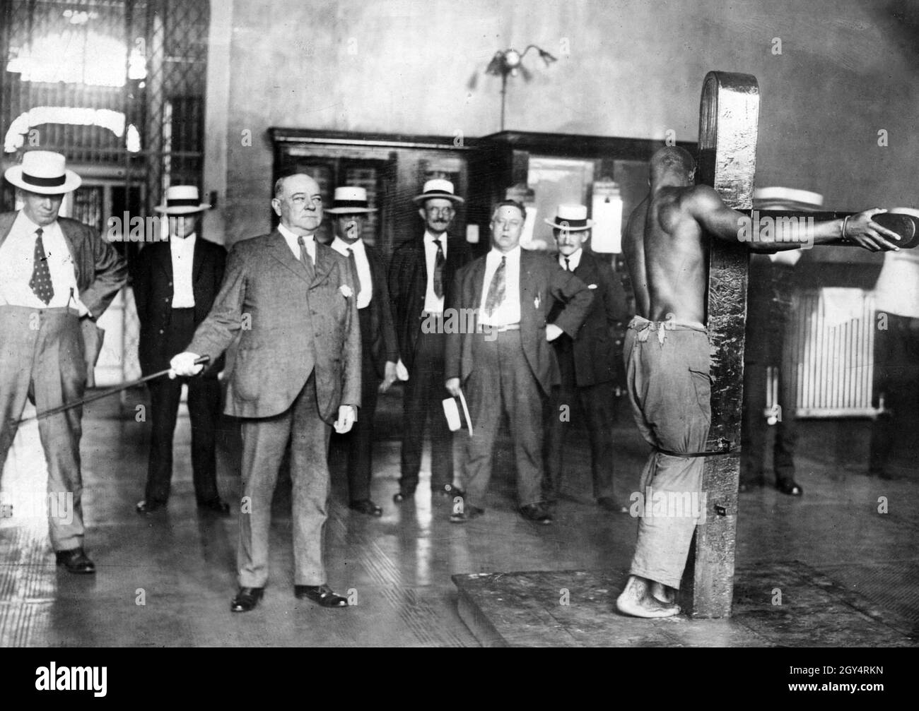 Ein afroamerikanischer Mann wird vor einer Gruppe weißer Männer geschlagen. [Automatisierte Übersetzung] Stockfoto