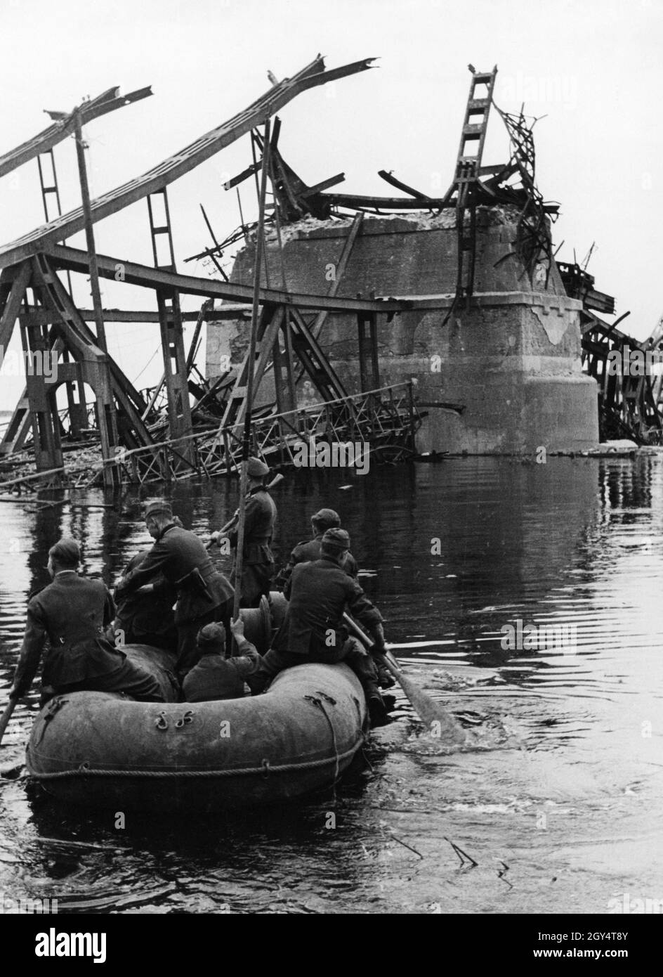 Deutsche Wehrmachtssoldaten sitzen in einem Schlauchboot und überfliegen  eine gesprengte Brücke. [Automatisierte Übersetzung] Stockfotografie - Alamy