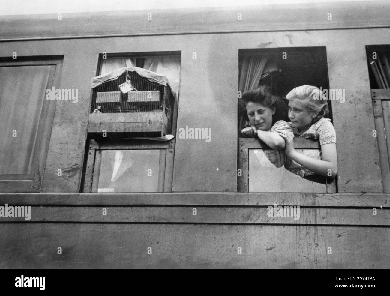 In der kleinen Stadt l'Ile Bouchard befindet sich ein Zug mit Flüchtlingen an Bord, der aus Paris angereist ist. Zwei Frauen blicken aus einem der Zugfenster. An einem der offenen Fenster im Zug steht ein Vogelkäfig. [Automatisierte Übersetzung] Stockfoto