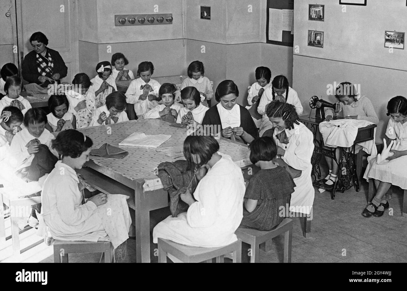 Die Mädchen lernen Sticken und Nähen an einer italienischen Schule. Es gibt eine Singer Nähmaschine im Zimmer. Das Bild wurde 1937 aufgenommen. [Automatisierte Übersetzung] Stockfoto