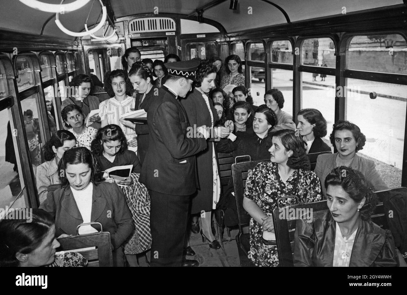 „Diese Frauen sind in die „Scuola per tranviere“ (Schule für Trambahnarbeiter) in Rom eingeschrieben. Im Juni 1940 müssen sie eine praktische Lerneinheit in einer Straßenbahn absolvieren. In der Mitte sieht der Inspektor eine Studentin beim Verkauf eines Tickets beobachten. [Automatisierte Übersetzung]' Stockfoto