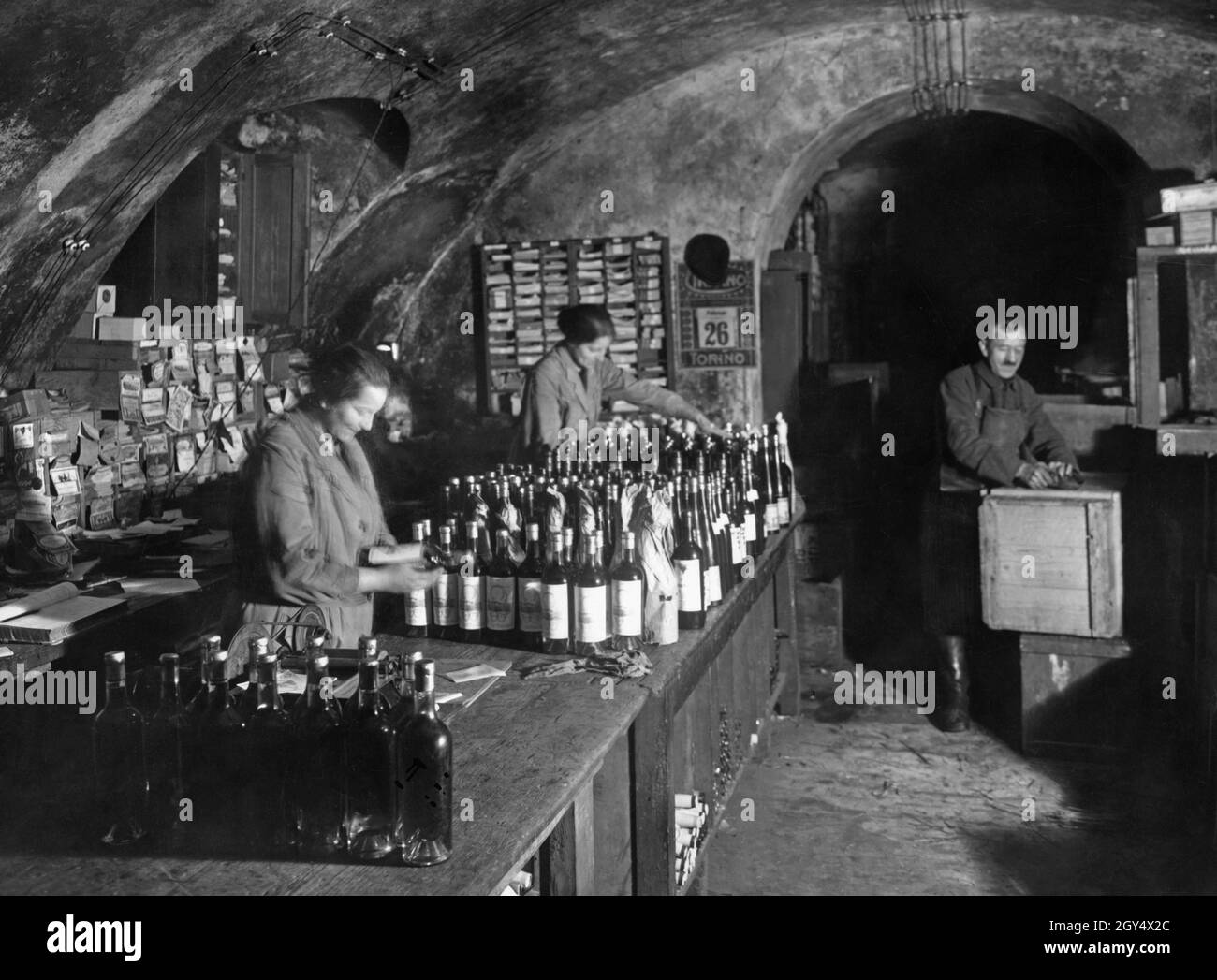 Arbeiter, die Flaschen im Keller eines Berliner Weinladens beschriften. [Automatisierte Übersetzung] Stockfoto