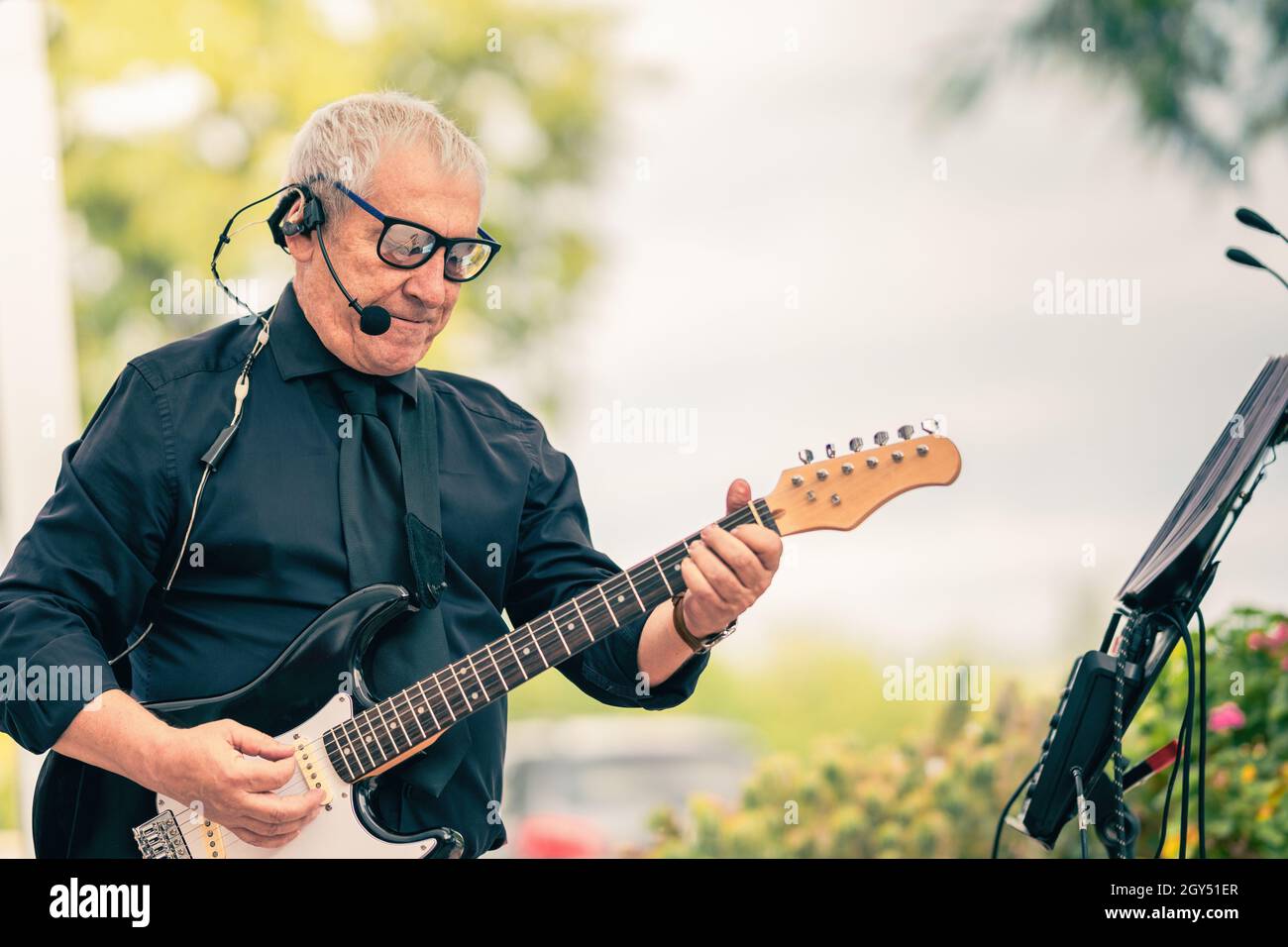 Foto mit Kopierraum eines alten Musikers, der die E-Gitarre im Freien spielt Stockfoto