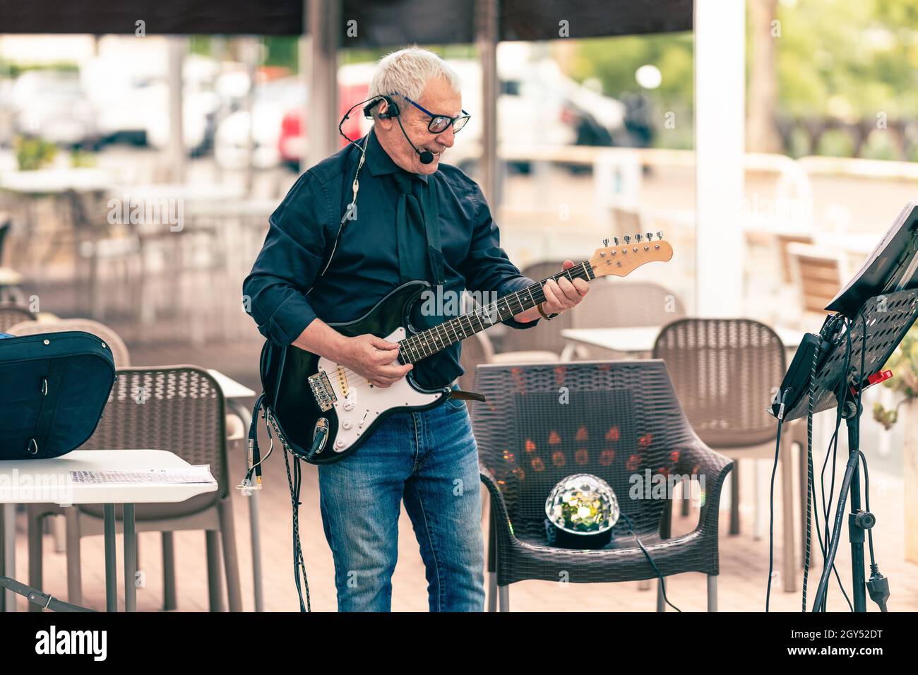Älterer Musiker, der auf einer Terrasse die E-Gitarre spielt Stockfoto