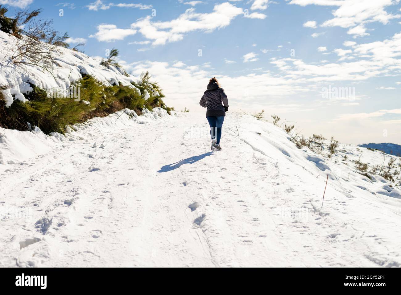 Eine junge Frau, die auf einem verschneiten Berg joggt Stockfoto