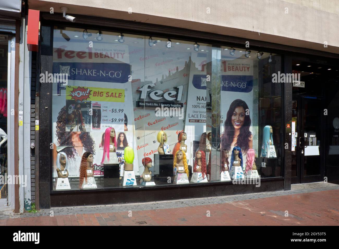 Markante, farbenfrohe Perücken zum Verkauf im Feel Beauty Supply, einem Perücke- und Kosmetikgeschäft an der Jamaica Avenue in Queens, New York City. Stockfoto