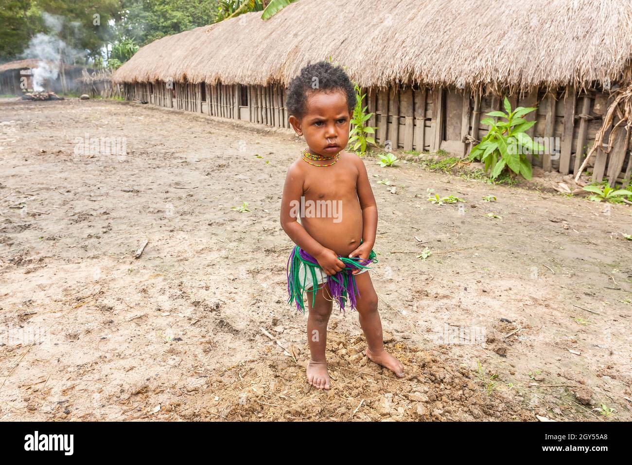 Wamena, Indonesien - 9. Januar 2010: Kind des Dani-Stammes steht in nea Strohhäusern, Papua-Neuguinea. Stockfoto