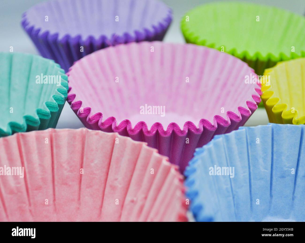 Leere, mehrfarbige Becher-Kuchenhüllen stehen auf einem Tablett bereit zum Befüllen Stockfoto