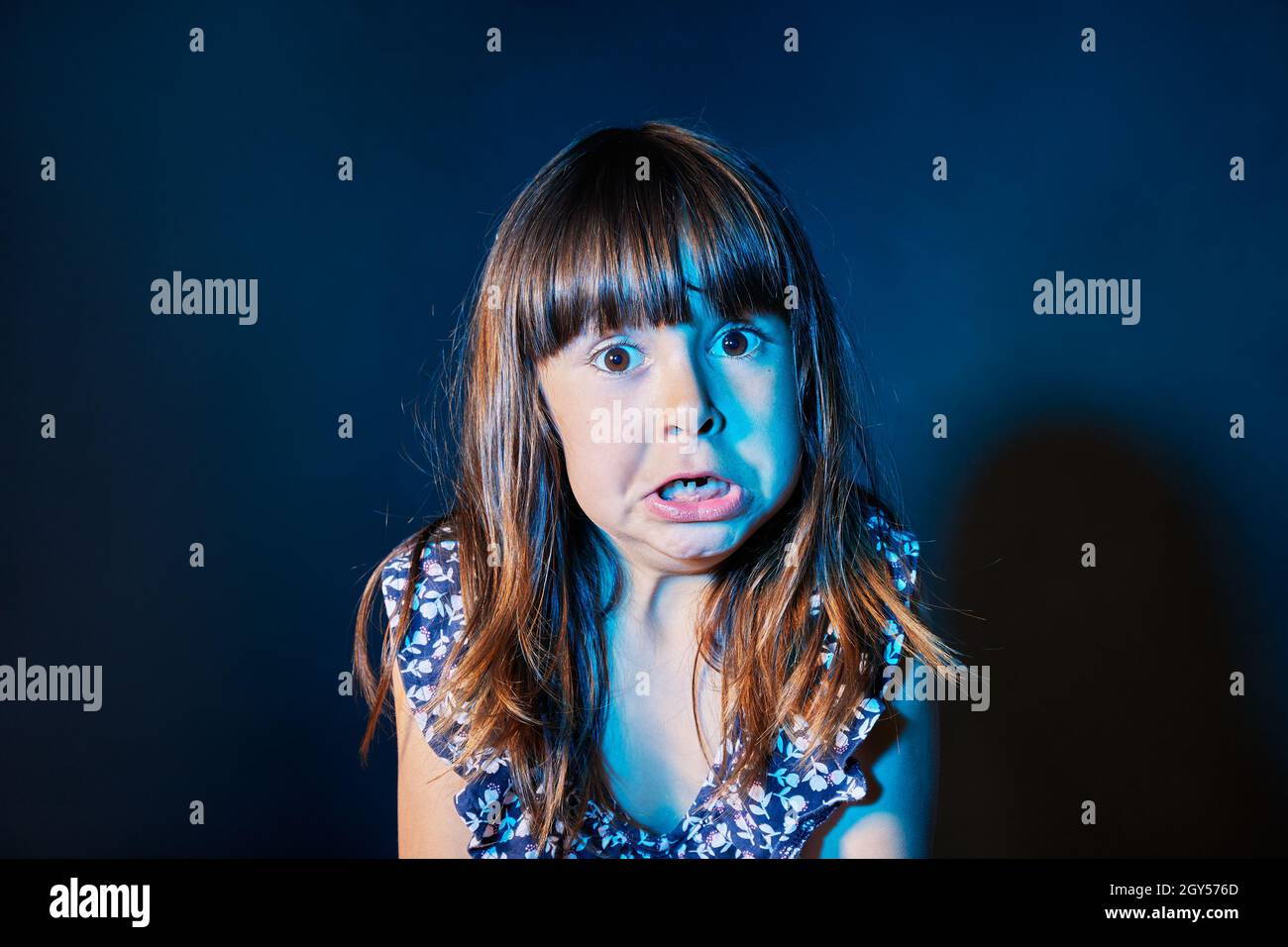 Porträt eines verängstigten Mädchens in einer dunklen Umgebung mit farbigen Lichtern Stockfoto