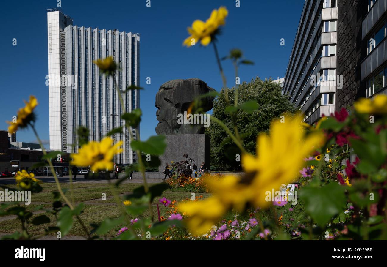Chemnitz, Deutschland. Oktober 2021. Bunte Blumen wachsen hinter dem Karl-Marx-Denkmal im Zentrum von Chemnitz. Die 'Nischel', wie die Chemnitzer ihre riesige Marx-Skulptur nennen, ziert Stempel, Tassen und Kreditkarten. Jetzt wird er 50. Der 40 Tonnen schwere, riesige bronzene Philosoph-Kopf gilt als die zweitgrößte Porträtbüste der Welt. Es wurde vom russischen Bildhauer Lew Curbel (1917-2003) geschaffen und am 9. Oktober 1971 vor 250,000 Menschen enthüllt. Quelle: Hendrik Schmidt/dpa-Zentralbild/dpa/Alamy Live News Stockfoto