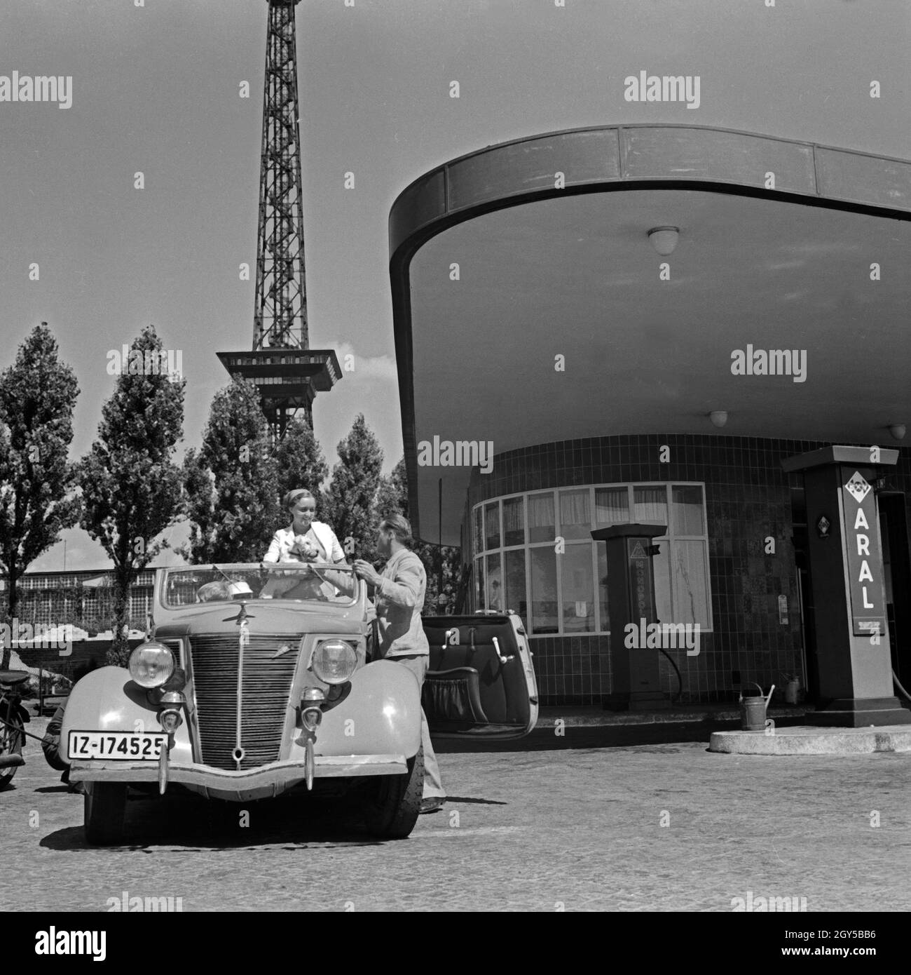 Eine Familie macht einen Zwischenstop bei einer Aral Tankstelle in der Nähe des Funkturms in Berlin, Deutschland, 1930er Jahre. Eine Familie hält an einer ARAL-Tankstelle in der Nähe der Berliner Funkturm, Deutschland 1930. Stockfoto