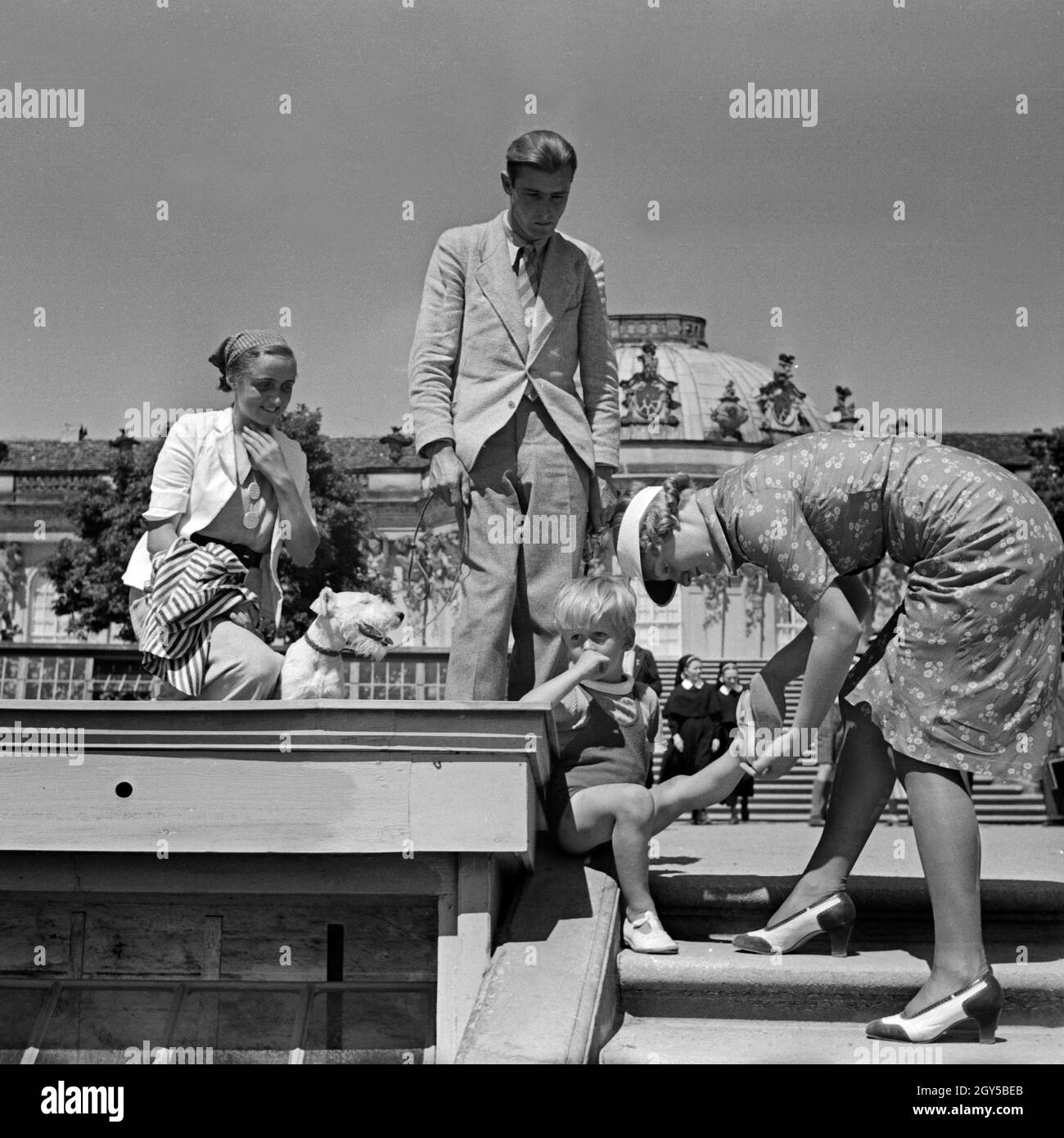 Eine Mutter hilft ihr kleiner Sohn vor der Fassade von Schloß Sanssouci in Potsdam bei Berlin, Deutschland 1930er Jahre. Eine Mutter hilft ihrem kleinen Jungen vor Schloss Sanssouci in Potsdam, in der Nähe von Berlin, Deutschland 1930er Jahre. Stockfoto