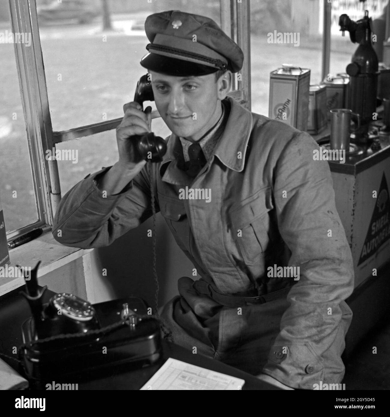 Der freundliche Mann von der Shell Tankstelle am Telefon, Deutschland 1930er Jahre. Die freundlichen Mitarbeiter an der Shell Tankstelle am Telefon, Deutschland 1930. Stockfoto